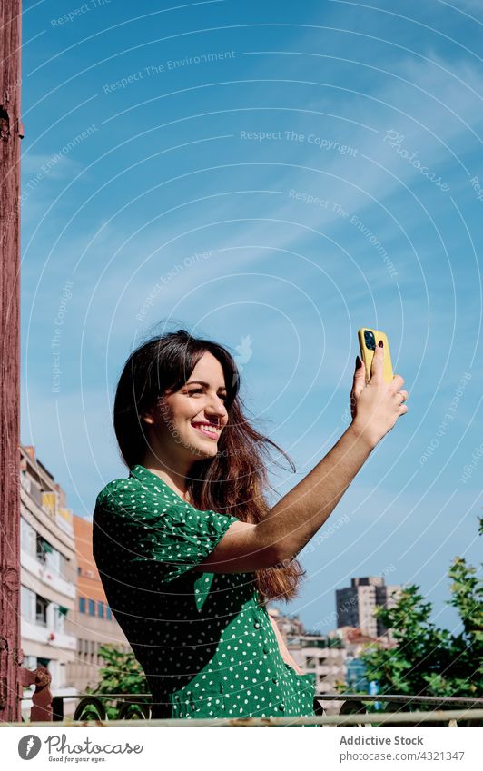 Zufriedene Frau macht Selfie auf Balkon Smartphone Selbstportrait Lächeln Sommer charmant heiter genießen Gerät Apparatur fotografieren benutzend Freude Glück