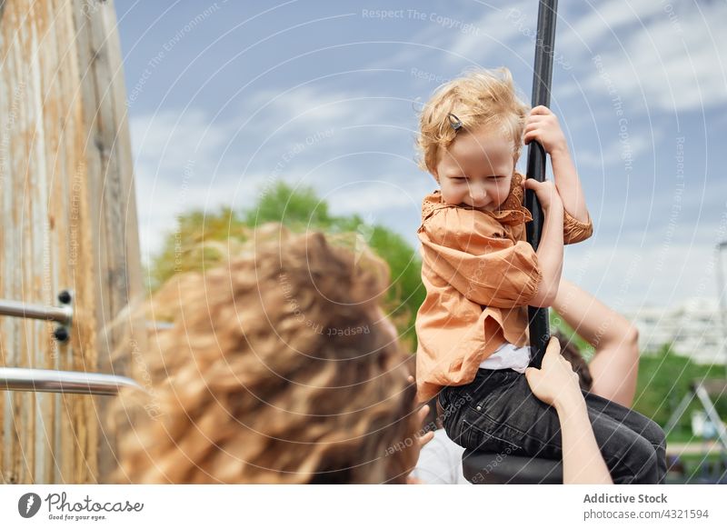 Niedliches Kind auf Seilschaukel auf Spielplatz mit Mutter spielen unterhalten Zusammensein Glück Spaß haben Mädchen Kindheit Park heiter pendeln Tochter Freude