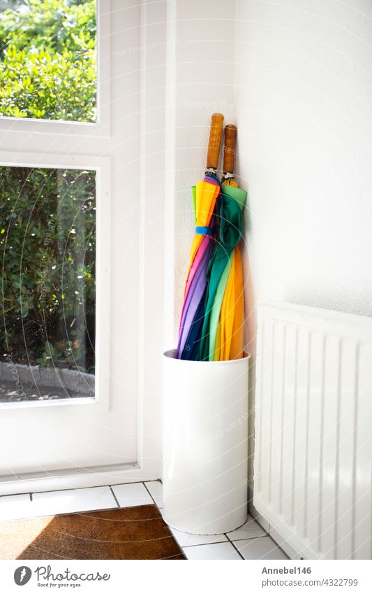 Regenschirm im Halter regenbogenfarbig in weißem Flur, modernes Design in hellem Haus neben der Tür bunt Klammer Hintergrund niemand Appartement Innenbereich