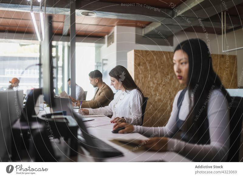 Unterschiedliche Kollegen arbeiten am Tisch im Büro Mitarbeiterin Menschengruppe Projekt Cowork Raum Arbeit beschäftigt Arbeitsplatz Zusammensein multiethnisch