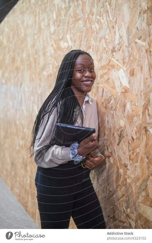 Schwarze Geschäftsfrau mit Tablet an einem modernen Arbeitsplatz Unternehmer Cowork Raum Lächeln Tablette Büro respektabel gut gekleidet Frau Afroamerikaner