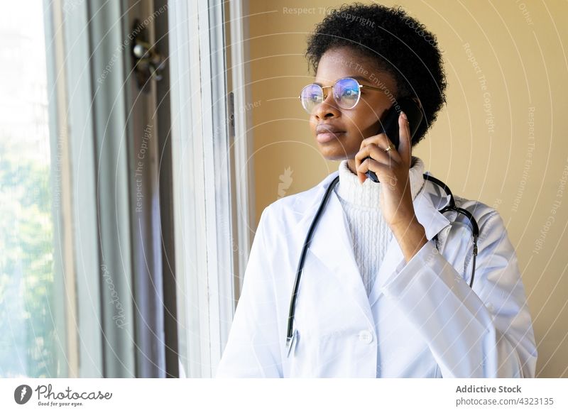 Schwarze Ärztin benutzt Smartphone in der Klinik Arzt Sanitäter benutzend Frau reden sprechen Gesundheitswesen Kommunizieren digital Telefon jung Afroamerikaner