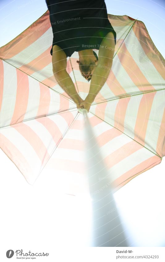 Mann stellt einen Sonnenschirm auf Sommer Sommerzeit Sommerurlaub Vorbereitung schützen Sonnenstrahlen Schatten schattenspender Urlaub Urlauber