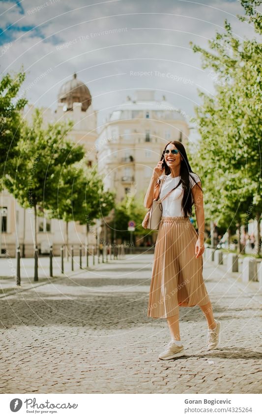 Junge Frau, die ein Mobiltelefon benutzt, während sie auf der Straße geht 20s Erwachsener attraktiv Tasche schön Sonnenbrille beschäftigt Anruf lässig Kaukasier