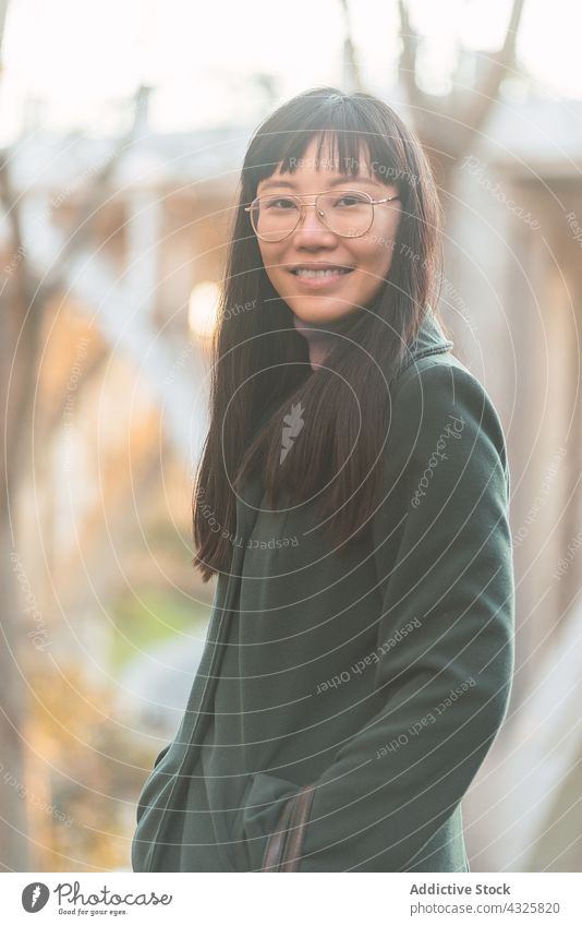 Lächelnde asiatische Frau im Herbstpark Park Mantel fallen charmant Inhalt Saison Großstadt ethnisch genießen Stil heiter froh sorgenfrei Outfit Vorschein