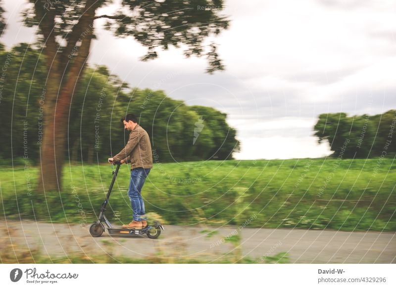 Mann fährt mit einem E-Roller fahren Natur außerhalb modern Elektroroller Zukunft Straße Lifestyle