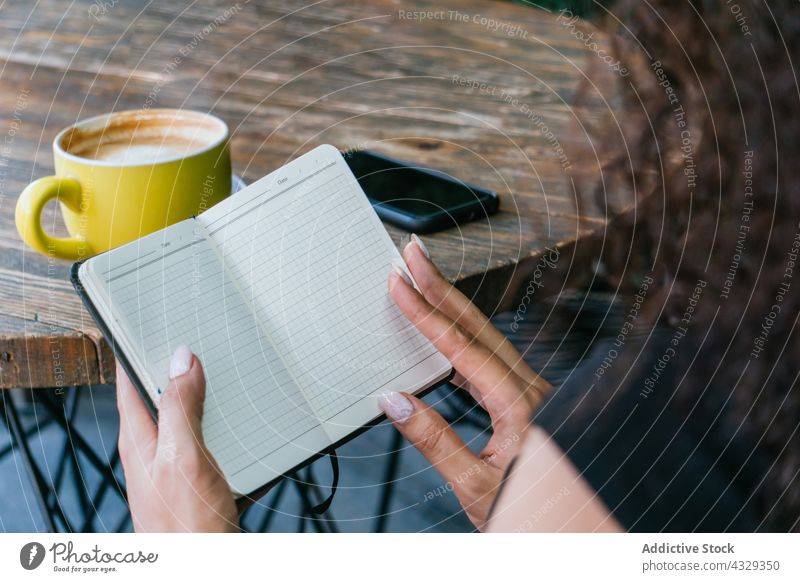 Frau blättert in einem Café in einem Notizbuch Notebook Kaffee Page lesen Planer leer Unternehmer beschäftigt Arbeit Terrasse Tasse freiberuflich Geschäftsfrau