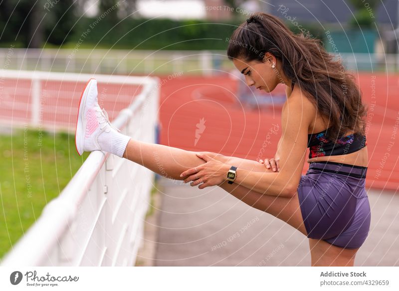 Sportlerin, die sich im Stadion die Beine vertritt Athlet Dehnung Läufer Aufwärmen Bahn Training Frau jung hispanisch ethnisch Übung Aktivität Lifestyle
