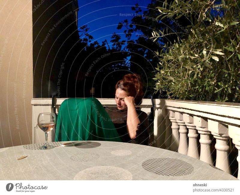 Nachdenkliche Frau mit Weinglas auf sommerlicher Terrasse am Abend nachdenklich dunkelhaarig Erwachsene 30-45 Jahre Sommer blaue Stunde Abenddämmerung Stimmung