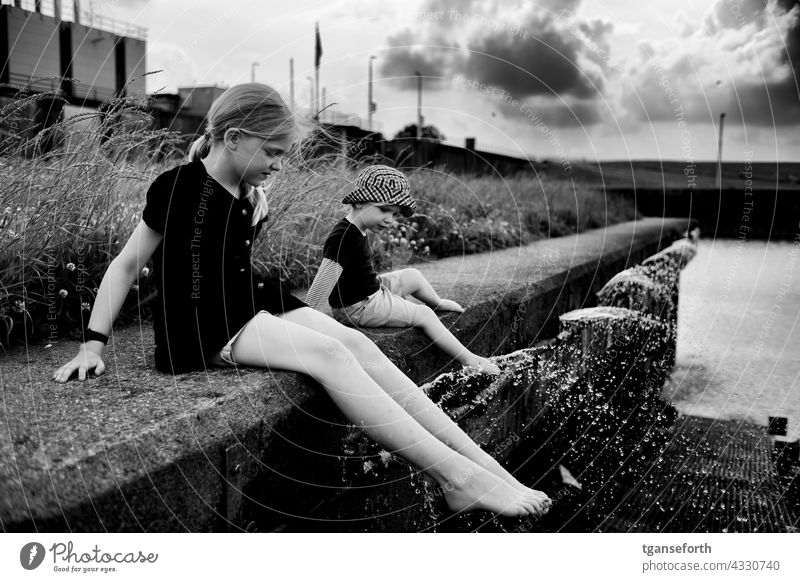 Kinder am Wasser abkühlung spritzen Füße kühlen Kaimauer Dollart Wassertropfen Erfrischung Schwimmen & Baden nass Sommer Außenaufnahme Kühlung Freude Spaß spiel