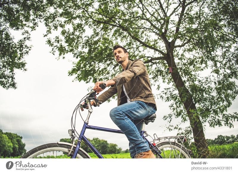 Mann sitzt auf einem Fahrrad sitzen Fahrradtour Pause überlegen Ausflug draußen Natur beobachten