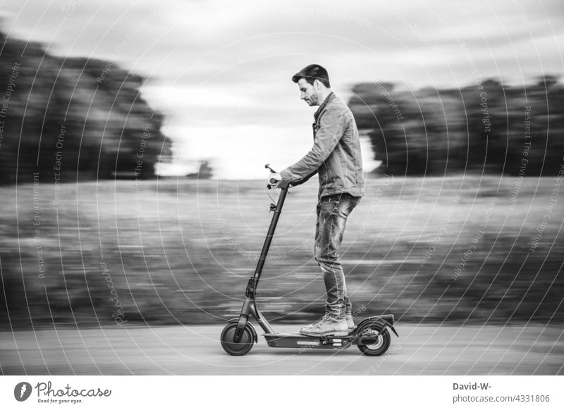 Mann fährt mit einem E-roller E-Roller Elektroroller fahren schnell unterwegs Zukunft Natur mobil Straße elektrisch modern