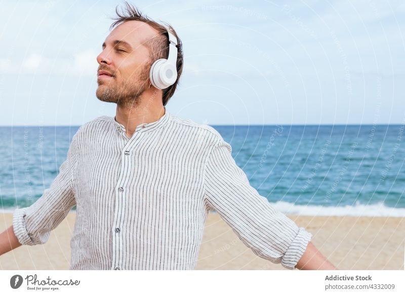 Entspannter Mann mit Kopfhörern genießt einen Sommertag am Strand sich[Akk] entspannen genießen Glück zuhören Musik MEER sorgenfrei männlich jung Vollbart