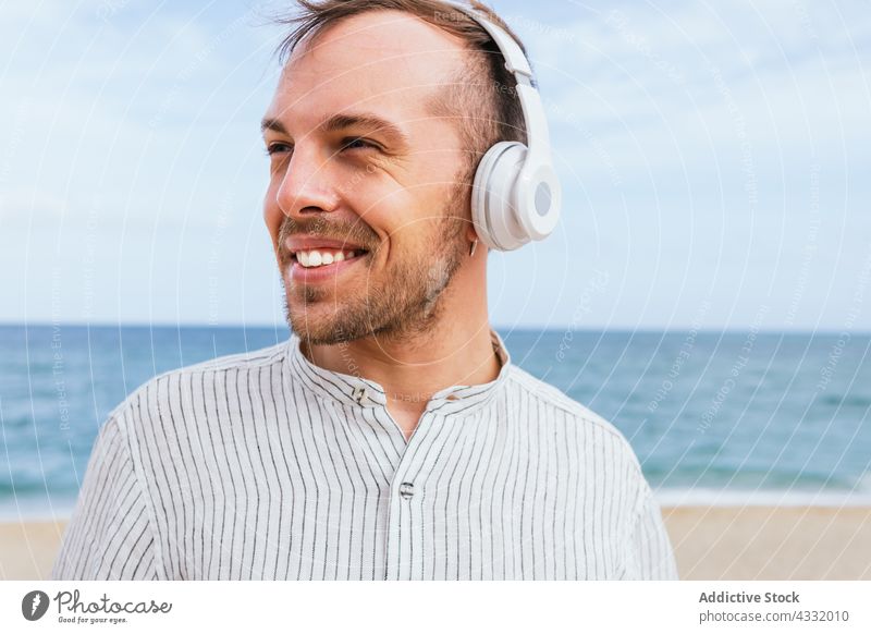 Glücklicher, entspannter Mann mit Kopfhörern genießt den Sommertag am Strand sich[Akk] entspannen genießen zuhören Musik MEER sorgenfrei männlich jung Lächeln