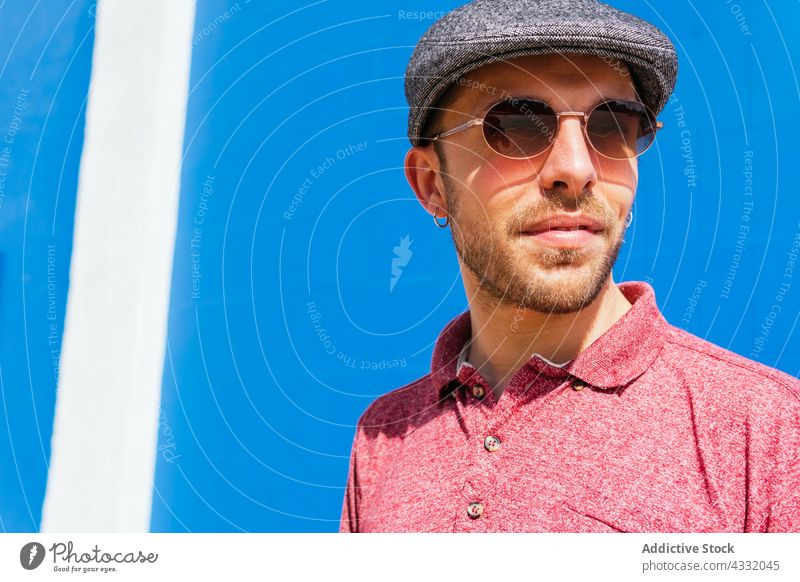 Mann in trendigem Outfit und Sonnenbrille auf blauem Hintergrund Stil Sommer trendy Vollbart urban männlich jung modern Hipster freundlich gutaussehend Polo