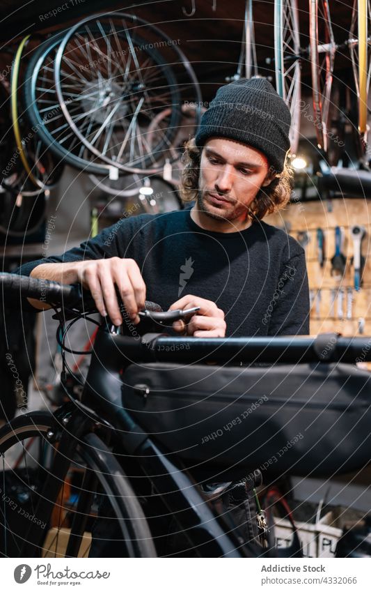 Konzentrierter Mann repariert Fahrrad in der Werkstatt fixieren Mechaniker Reparatur Lenker Dienst Meister männlich Garage beschäftigt Werkzeug Arbeit Fahrzeug