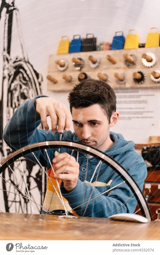 Mann repariert ein Fahrradrad in einer Werkstatt fixieren Rad Speiche Rand Mechaniker Reparatur männlich Dienst Hobelbank Meister Garage beschäftigt Werkzeug