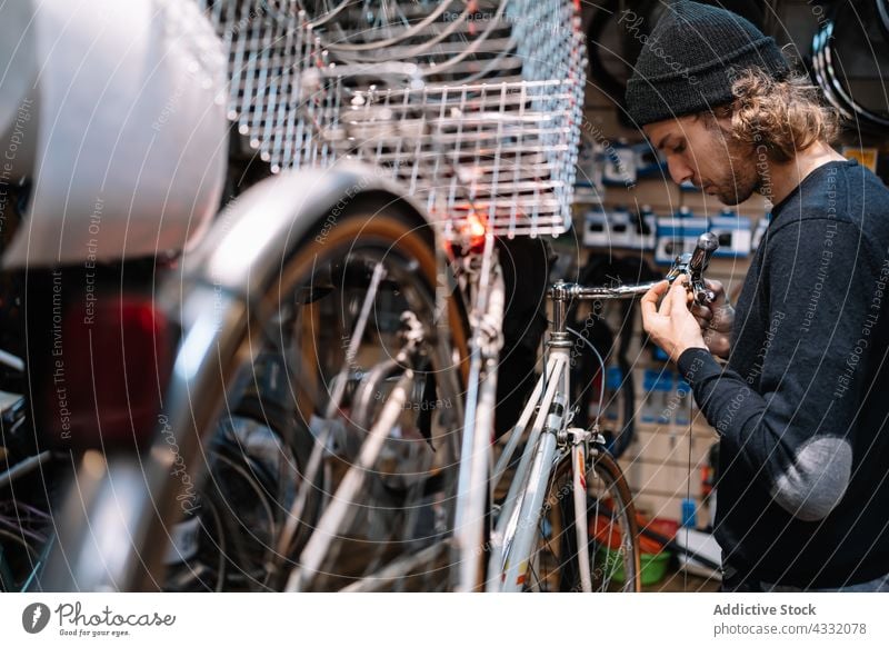 Mann bei der Reparatur von Fahrrädern in einer Werkstatt Fahrrad fixieren Garage Arbeit Mechaniker Dienst männlich Fahrzeug Job professionell Verkehr