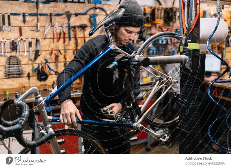Konzentrierter Mann repariert Fahrrad in Garage fixieren Rad Werkstatt Reparatur Mechaniker Arbeit männlich Dienst Fahrzeug Job professionell Verkehr