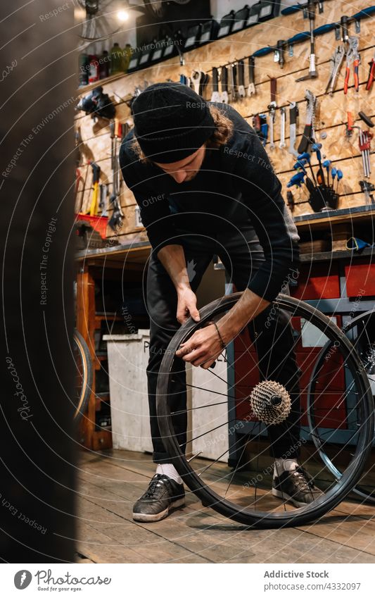 Konzentrierter Mann repariert Fahrrad in Garage fixieren Rad Werkstatt Reparatur Mechaniker Arbeit männlich Dienst Fahrzeug Job professionell Verkehr