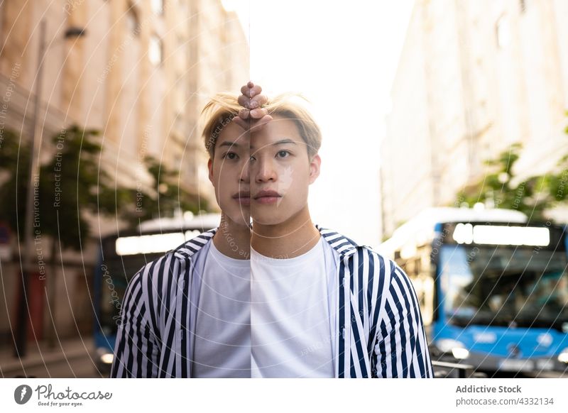 Asiatischer Mann steht in der Nähe einer Glaswand in der Stadt Model Reflexion & Spiegelung Großstadt reflektieren Straße Stil selbstbewusst männlich ethnisch