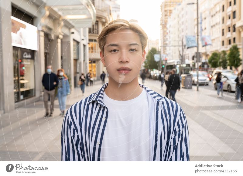 Stilvoller ethnischer Mann in der Stadt urban Straße blond Model Großstadt trendy männlich asiatisch modern Rucksack Lifestyle Outfit ernst jung selbstbewusst