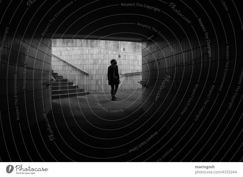 Deprimierte Frau geht durch einen Tunnel Fußgängertunnel Schwarzweißfoto schwarzweiß Schwarzweißfotografie Depression deprimiert niedergeschlagen