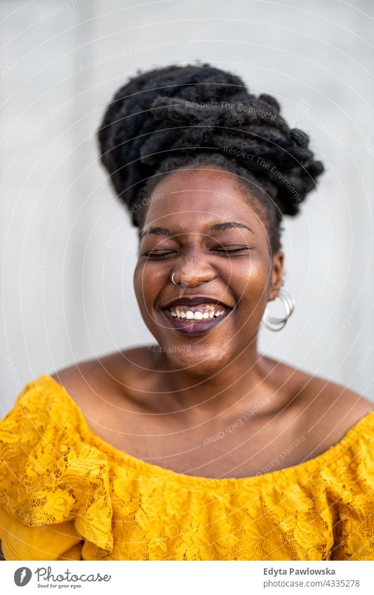 Fröhliche Frau vor einer Mauer Rastalocken stolz echte Menschen Stadtleben Afroamerikaner Afrikanisch schwarz Ethnizität sonnig Sonnenuntergang außerhalb