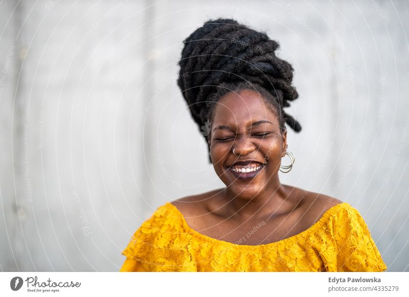 Fröhliche Frau vor einer Mauer Rastalocken stolz echte Menschen Stadtleben Afroamerikaner Afrikanisch schwarz Ethnizität sonnig Sonnenuntergang außerhalb