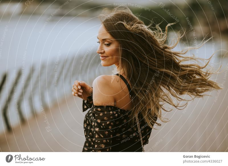 Junge lange Haare brünette Frau zu Fuß auf dem Flussufer Kaukasier Person Behaarung Porträt Kleid Schönheit Lächeln schön Model jung allein hübsch Lifestyle