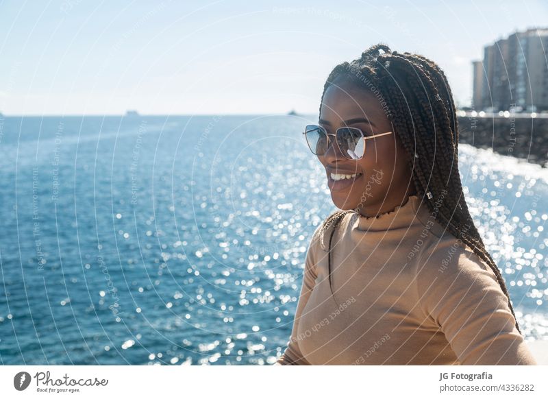 Porträt des jungen schwarzen Mädchen lächelnd mit blauem Meer Hintergrund Frau Lächeln Lifestyle Menschen Afro-Look Himmel MEER Glück im Freien Erwachsener