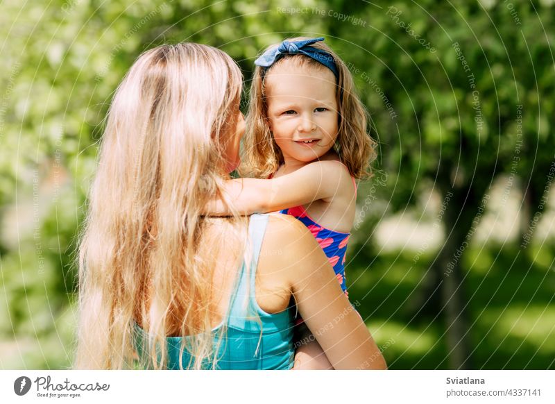 Eine junge Mutter hält ihre kleine Tochter in den Armen an einem Sommertag im Garten oder Park wenig Familie Eltern Mama Kind Kindheit Glück
