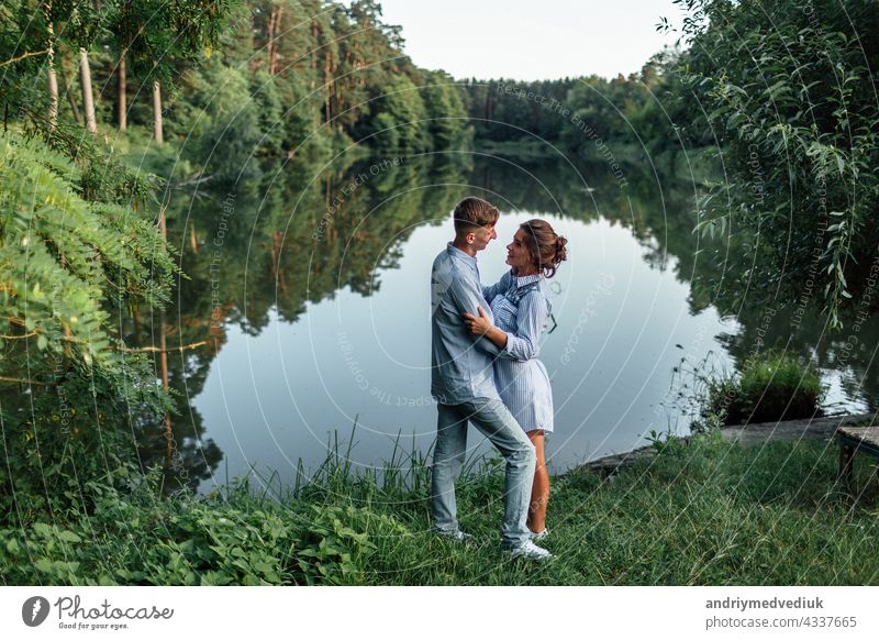 Junges Paar ist umarmt und zu Fuß in der Nähe des Sees am sonnigen Tag. Mann und Frau im Sommerurlaub. Konzept der schönen Familie. selektiver Fokus jung