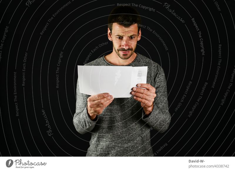 skeptisch schaueneder Mann öffnet einen Briefumschlag Post öffnen ängstlich Blick Information Nachricht schockiert Angst Mitteilung