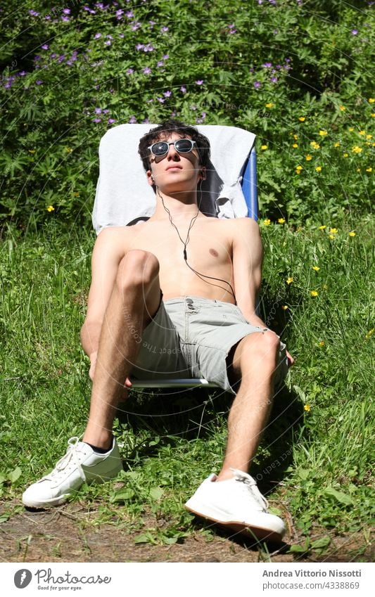 Junge beim Sonnenbad auf einer Sonnenliege mit Platz für Ihren Text Teenager im Freien Holz Sitzen Stuhl Sonnenbank Kaukasier männlich Freizeit Urlaub Feiertag