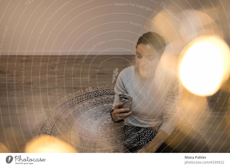 Junge Frau in warmer Atmosphäre mit Lichtern starrt auf ihr Handy Smartphone Technik & Technologie Telefon Hände Internet benutzend Mobile modern Lifestyle jung
