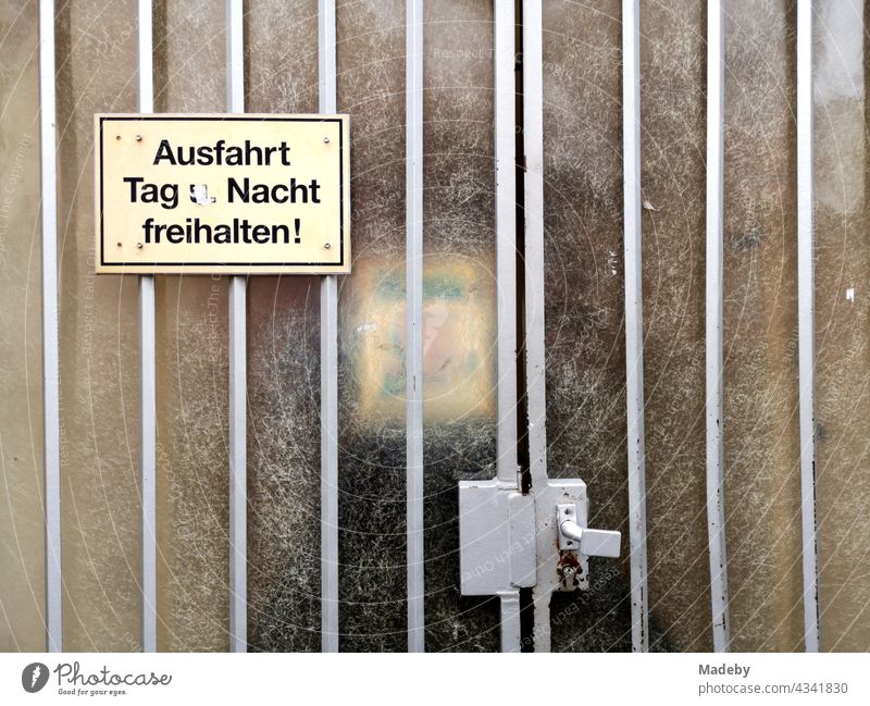 Gelbes Plastikschild an einem alten Tor mit Riffelglas vor einer Hofeinfahrt in Offenbach am Main in Hessen Schild vergilbt Verbot warnung Ausfahrt Hinweis