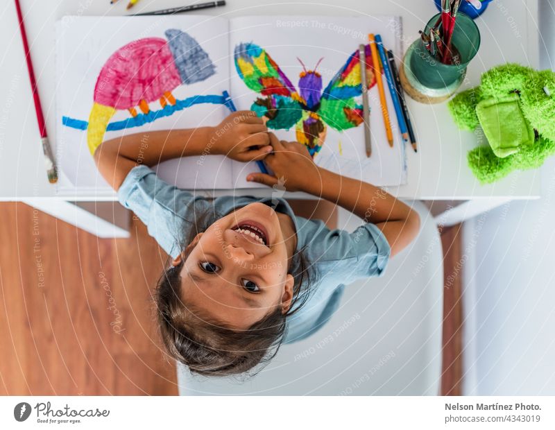 Draufsicht auf ein Mädchen, das zu Hause auf dem Tisch malt Farbe Glück spielerisch Frau Kinder spielen jung Fröhlichkeit Person Kunst Papier Inspiration wenig