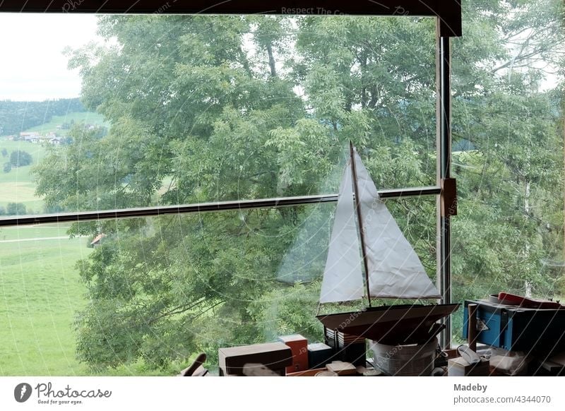 Schönes Holzmodell einer Segelyacht mit weißen Segeln auf der Werkbank in einer ausgebauten alten Scheune mit Panoramafenster auf einem Bauernhof in Rudersau bei Rottenbuch im Kreis Weilheim-Schongau in Oberbayern