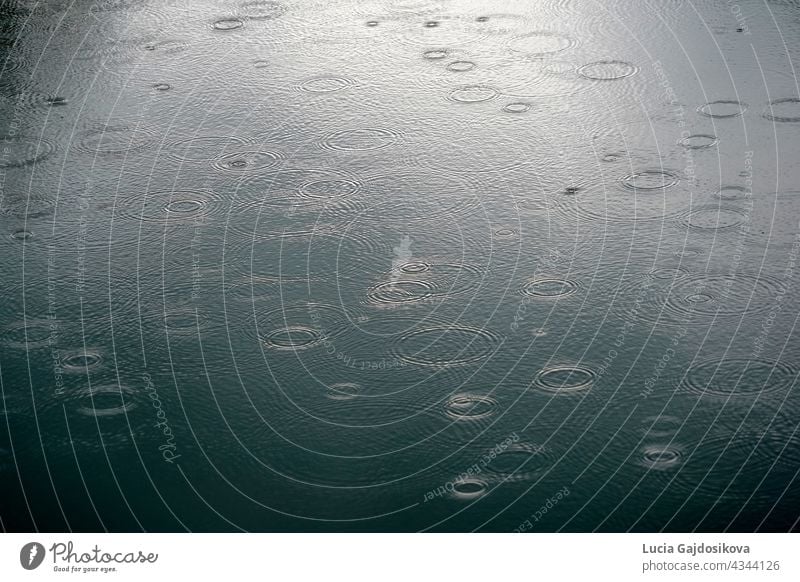 Regentropfen fallen die Oberfläche auf Fluss machen Kreise auf dem Wasser. Bild geeignet als Hintergrund. abstrakt abstrakter Hintergrund Schaumblase