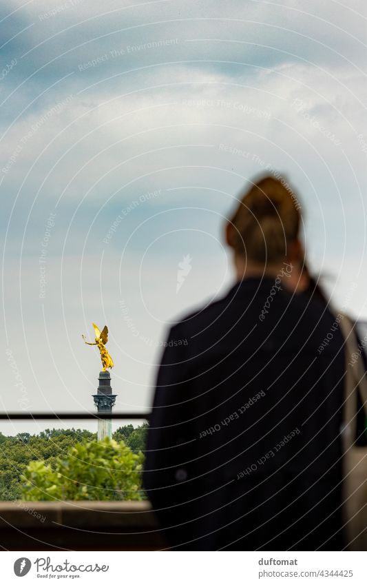 Frau blickt auf Münchner Friedensengel München Tourismus Engel Bayern gold golden ausblick ausblick genießen Ferne Heimat Wolken Wolkenhimmel Rücken