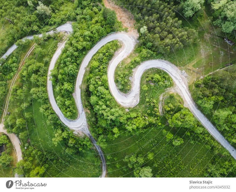 Drohnenansicht einer schönen Serpentinenstraße, die durch eine Berglandschaft im Sommer führt.  Luftbildaufnahme einer Straße, aufgenommen mit einer Drohne.  Beschädigte Straßenoberfläche