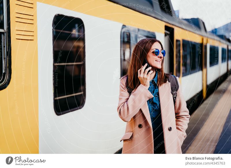 glückliche Backpacker kaukasische Frau auf dem Bahnsteig auf dem Bahnhof im Gespräch auf dem Mobiltelefon. Reisen Konzept Handy reisen Kaukasier Glück