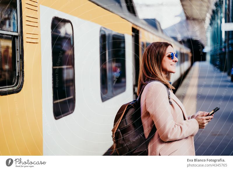 glückliche Backpacker kaukasische Frau am Bahnsteig auf Bahnhof mit Handy. Reisen Konzept reisen Kaukasier Glück Technik & Technologie Rucksack tagsüber Porto