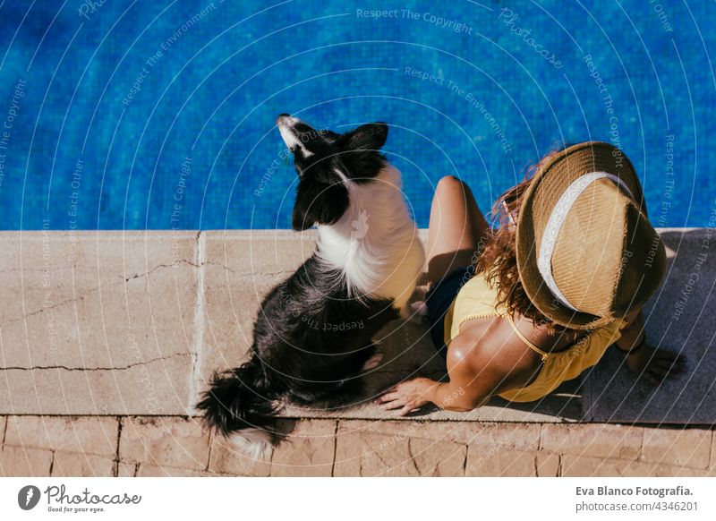 Draufsicht auf junge kaukasische Frau sitzt am Pool Seite mit niedlichen Border Collie Hund. Sommerzeit, Urlaub und Lifestyle Schwimmbad Zusammensein Liebe
