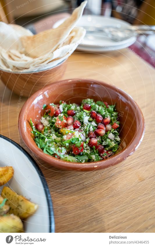 Nahaufnahme eines leckeren Tabbouleh-Salats mit Granatapfelkernen in einer braunen Keramikschale tabbouleh Salatbeilage Samen Saatgut Mezze Tisch Snack Libanese