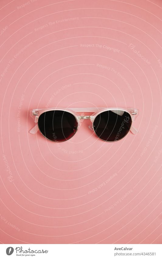 Minimalistische Aufnahme einer Sonnenbrille über einem pastellrosa Hintergrund mit Kopierraum, Design und Sommerkonzepten sehr wenige Pastell tropisch trendy