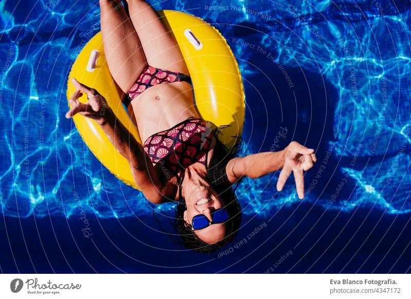 Draufsicht auf glückliche kaukasische Frau, die sich auf gelben Donuts aufblasbaren am Swimmingpool entspannt. Sommerzeit, Urlaub und Lebensstil Kaukasier