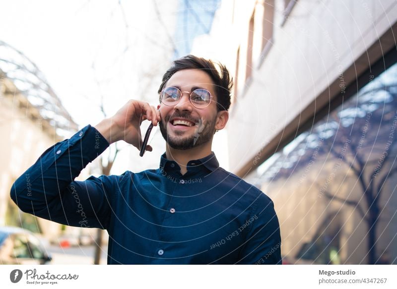 Junger Mann beim Telefonieren im Freien. jung Mobile urban Lächeln Anschluss Apparatur Porträt positiv Drahtlos Beteiligung laufen Blick Tippen sprechend reden