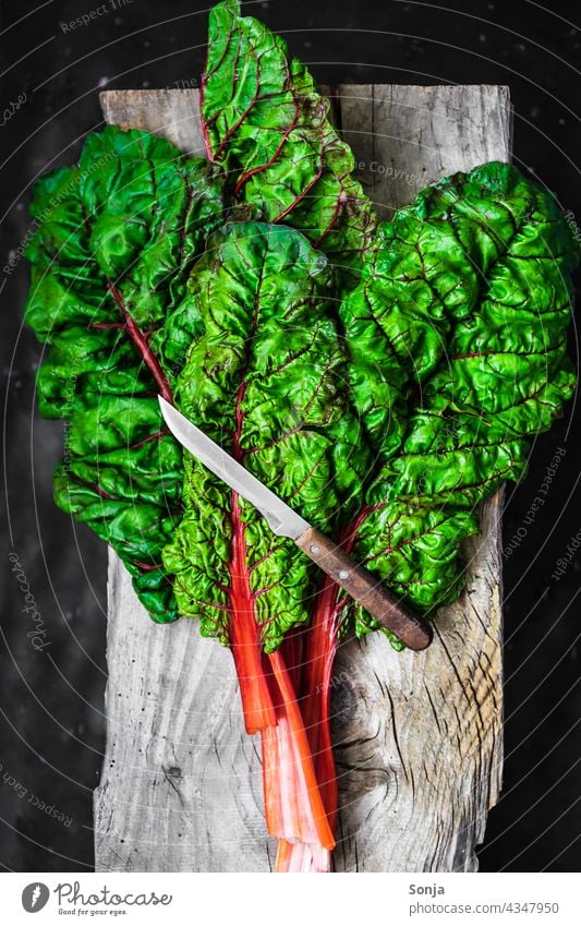 Frische rohe Mangoldblätter und ein Messer auf einem Holz Schneidebrett Blätter rustikal Gemüse Vegetarische Ernährung Zutaten grün Gesundheit organisch reif